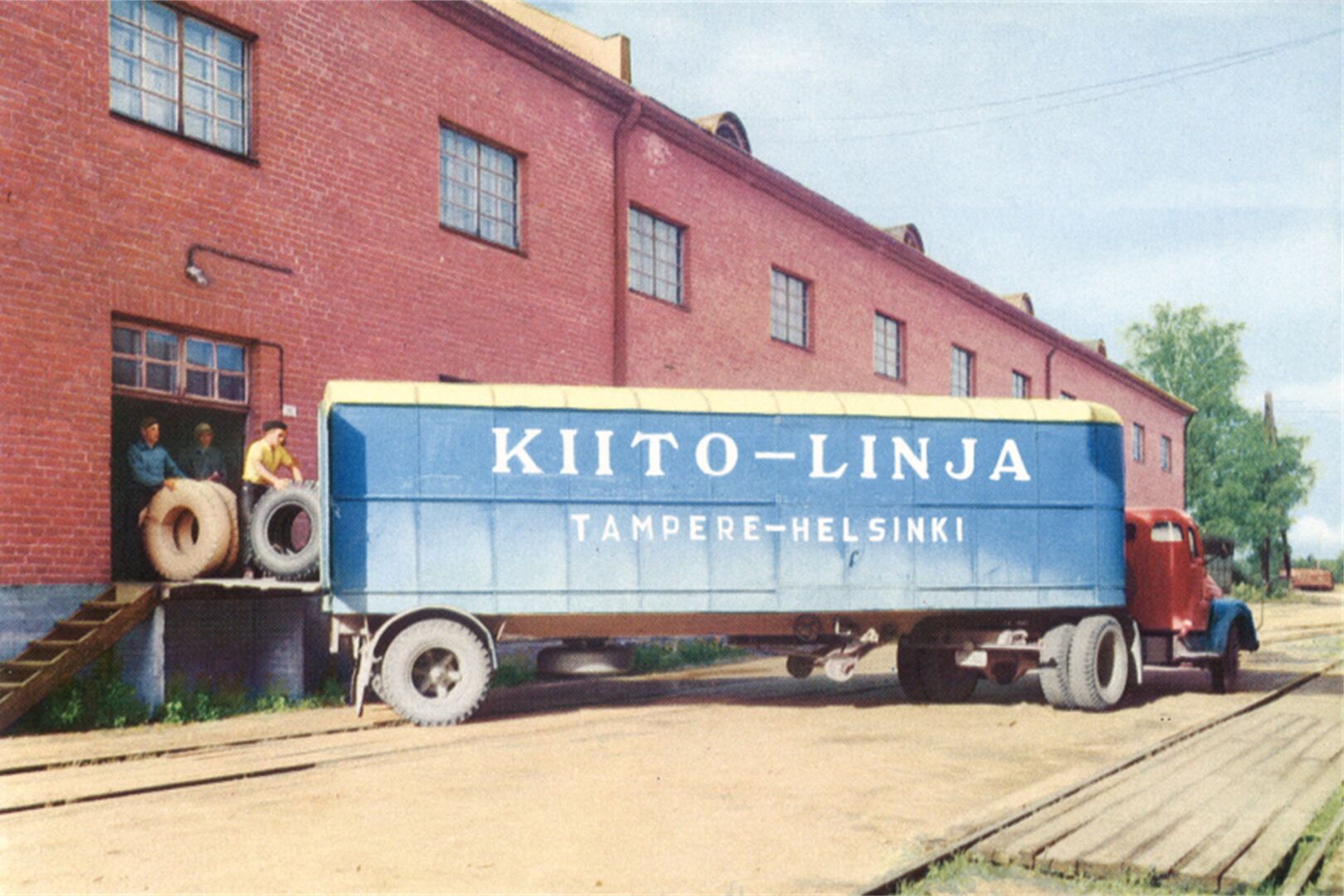 Kiitolinjan kuorma-auto rakennuksen edessä lastattavana