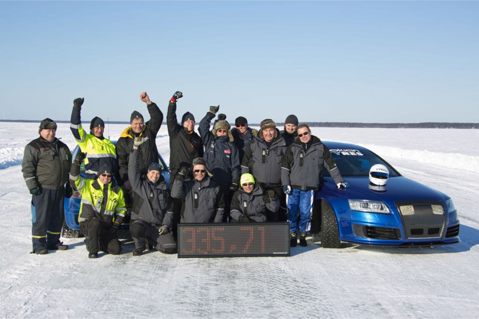 Maailmanennätyksen tehnyt porukka hurraa autonsa ja aikansa vieressä