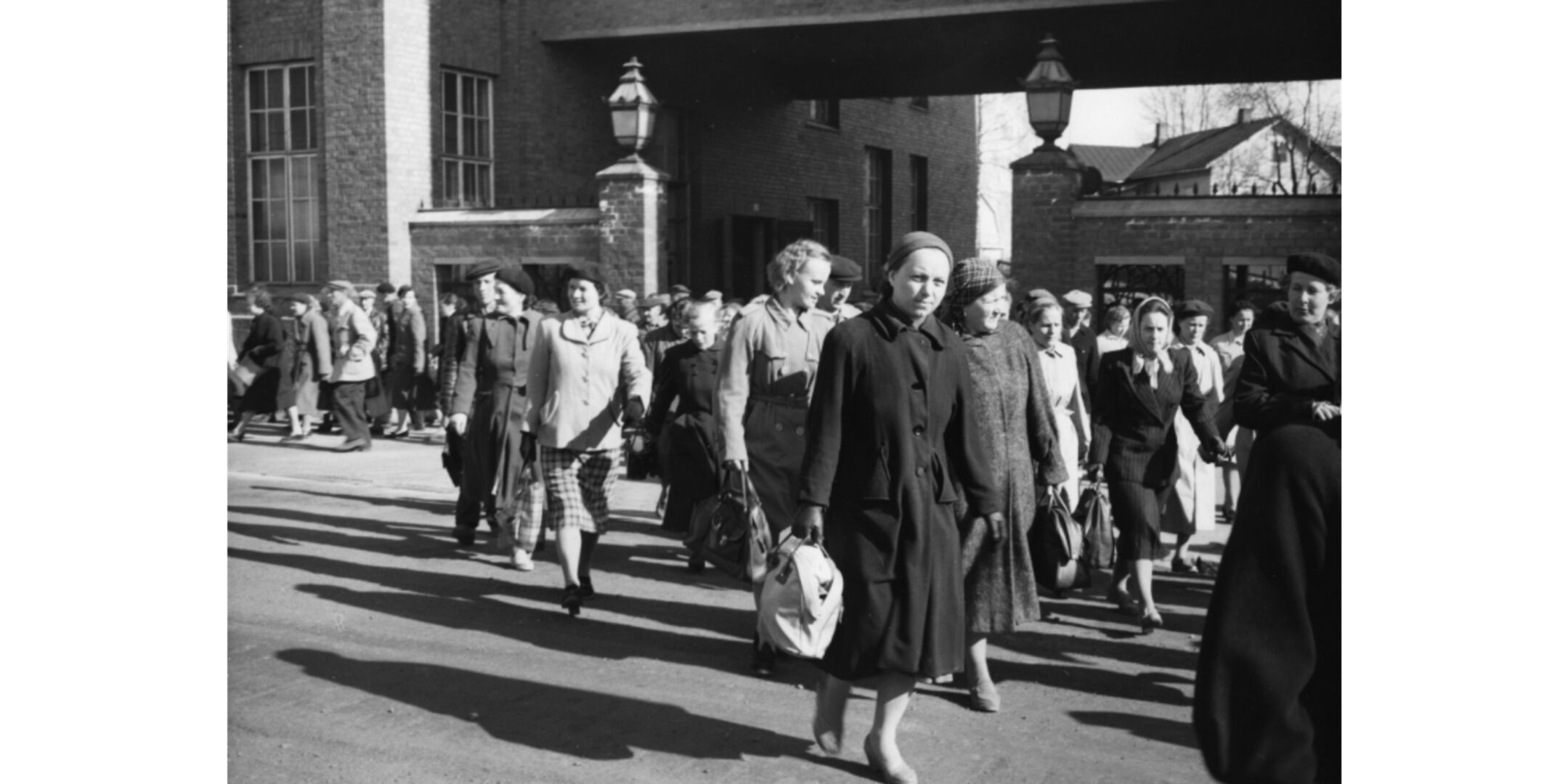 Old photo of Nokian Tyres' employees walking home from the factory behind them