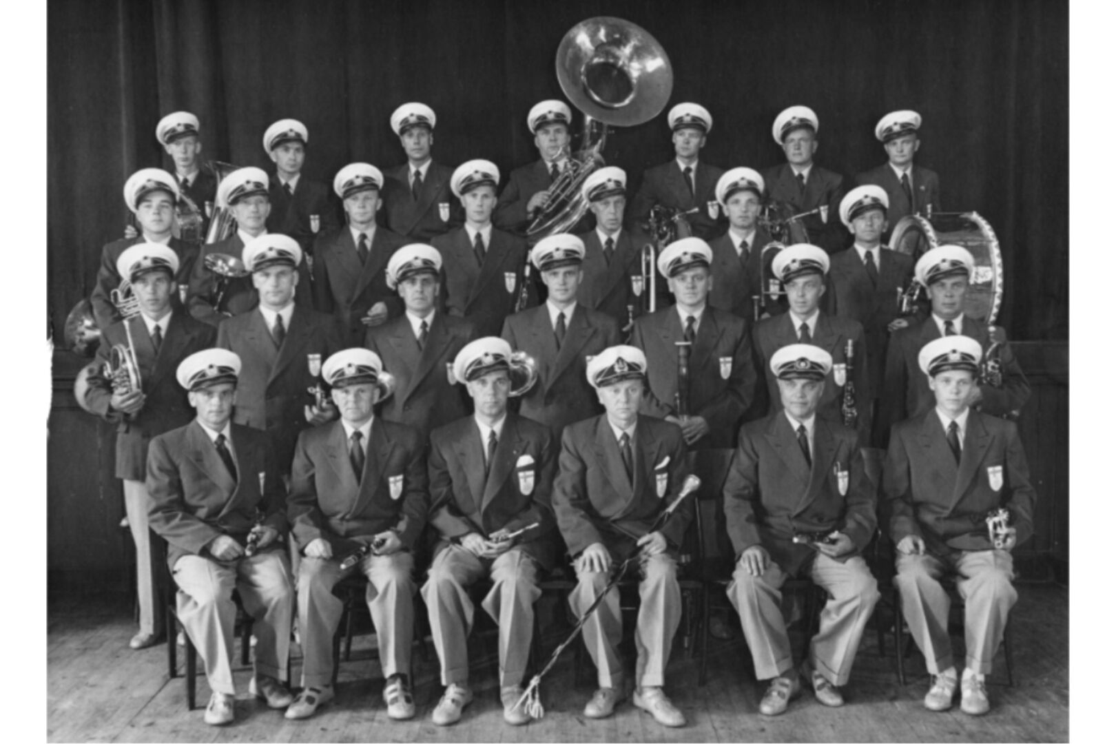An old photo of the memebers of the Gummitehdas band arranged in rows.