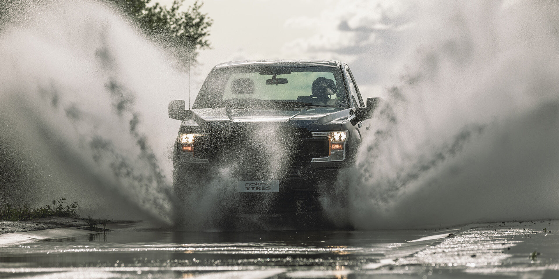 Car passing a puddle, water splashes high