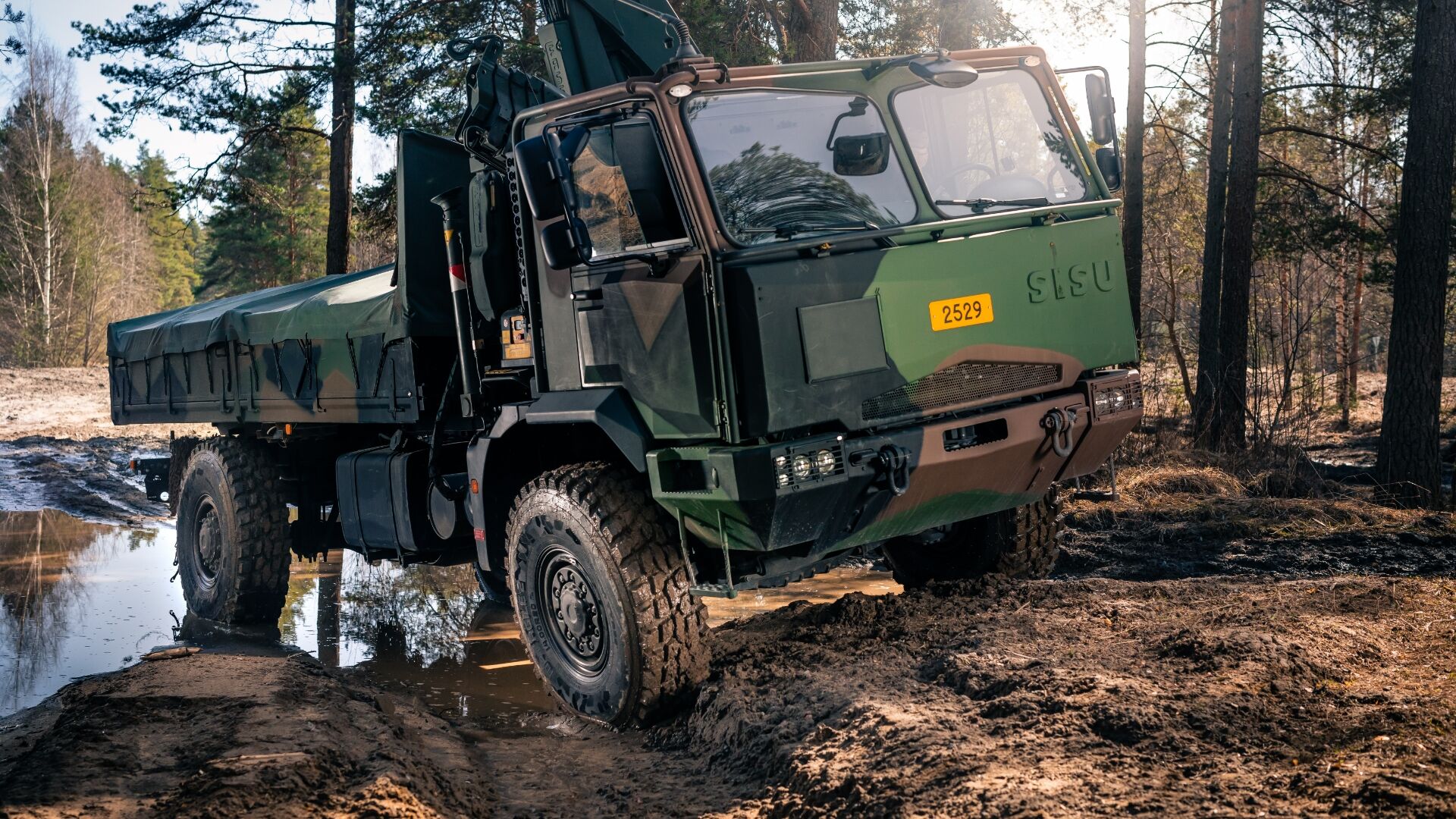 Un camión militar en el bosque sobre una superficie irregular y embarrada