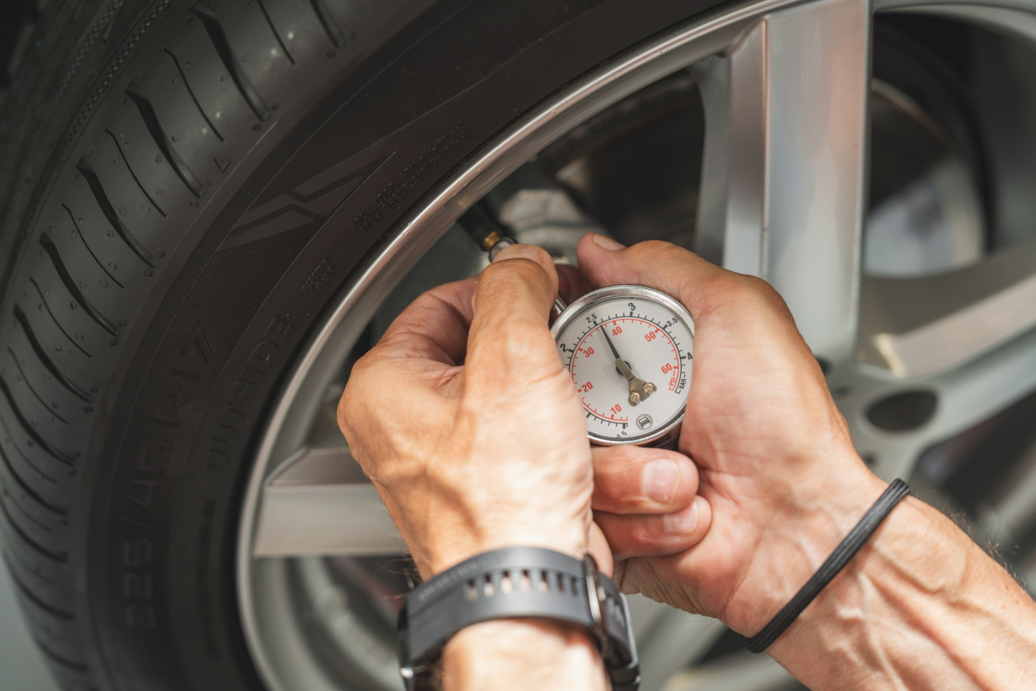 Persons hands using a meter to check tire pressure