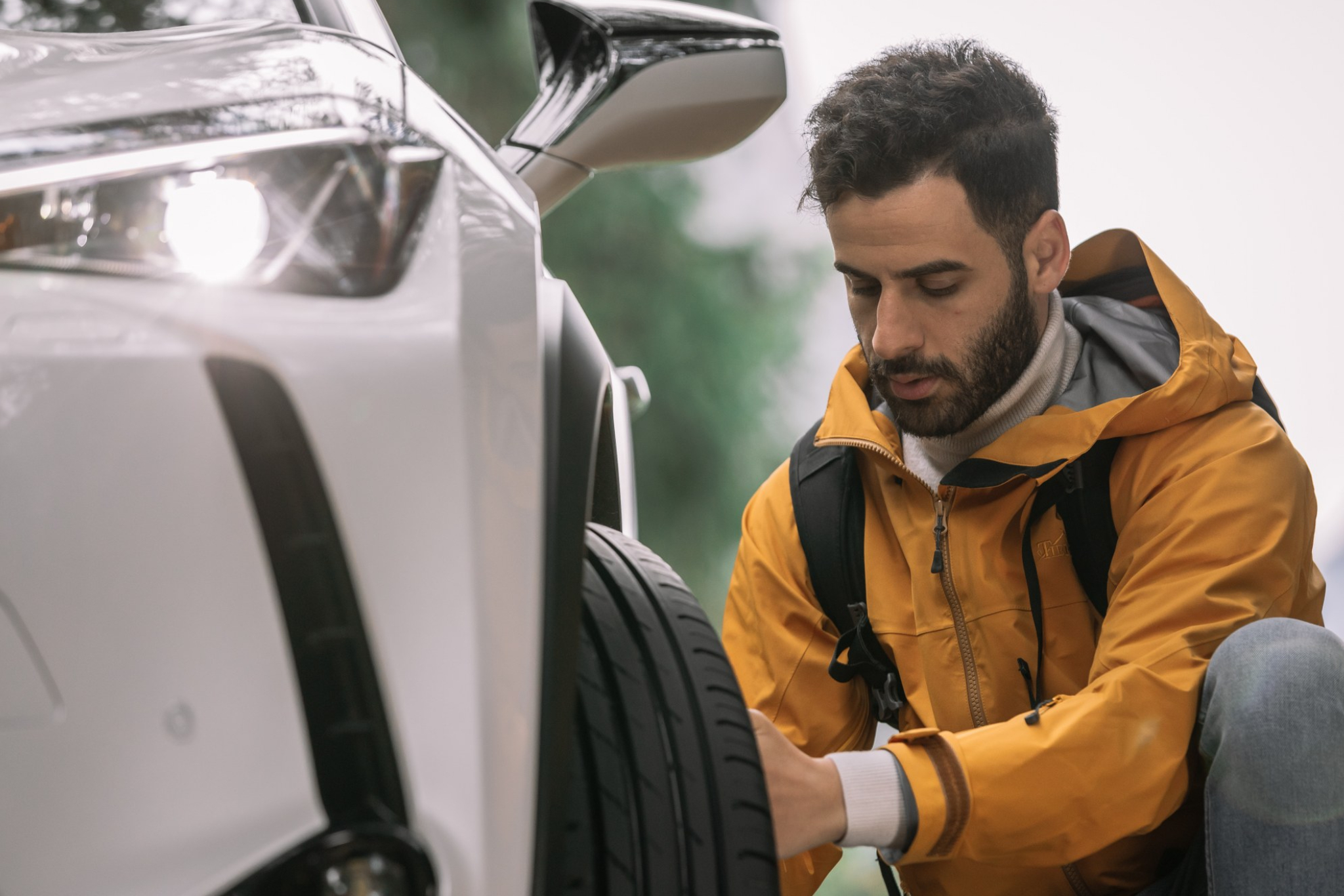 Man checking the tire on the front of the car