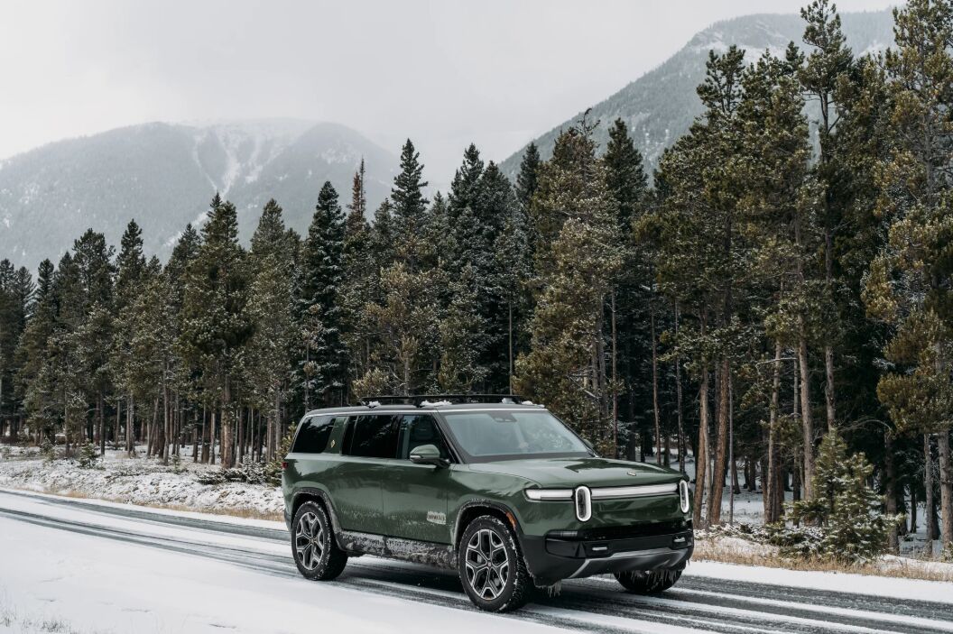 A Rivian R1 traveling through a forest on a wintery road with Hakkapeliitta R5 SUV winter tires